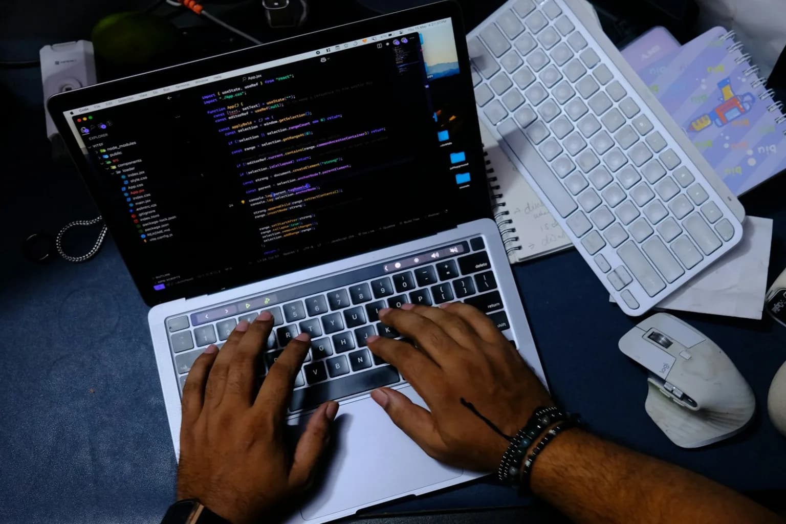 Hands working on React code in Visual Studio Code on a laptop
