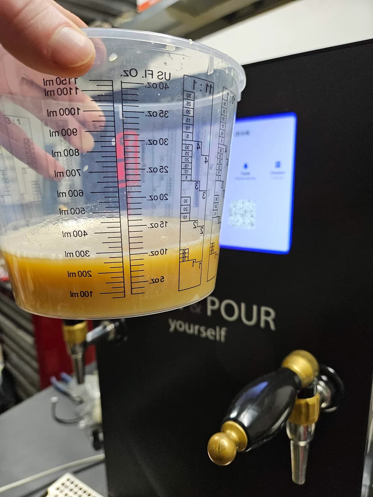 A measuring jug held beside the dispenser during a pouring test.