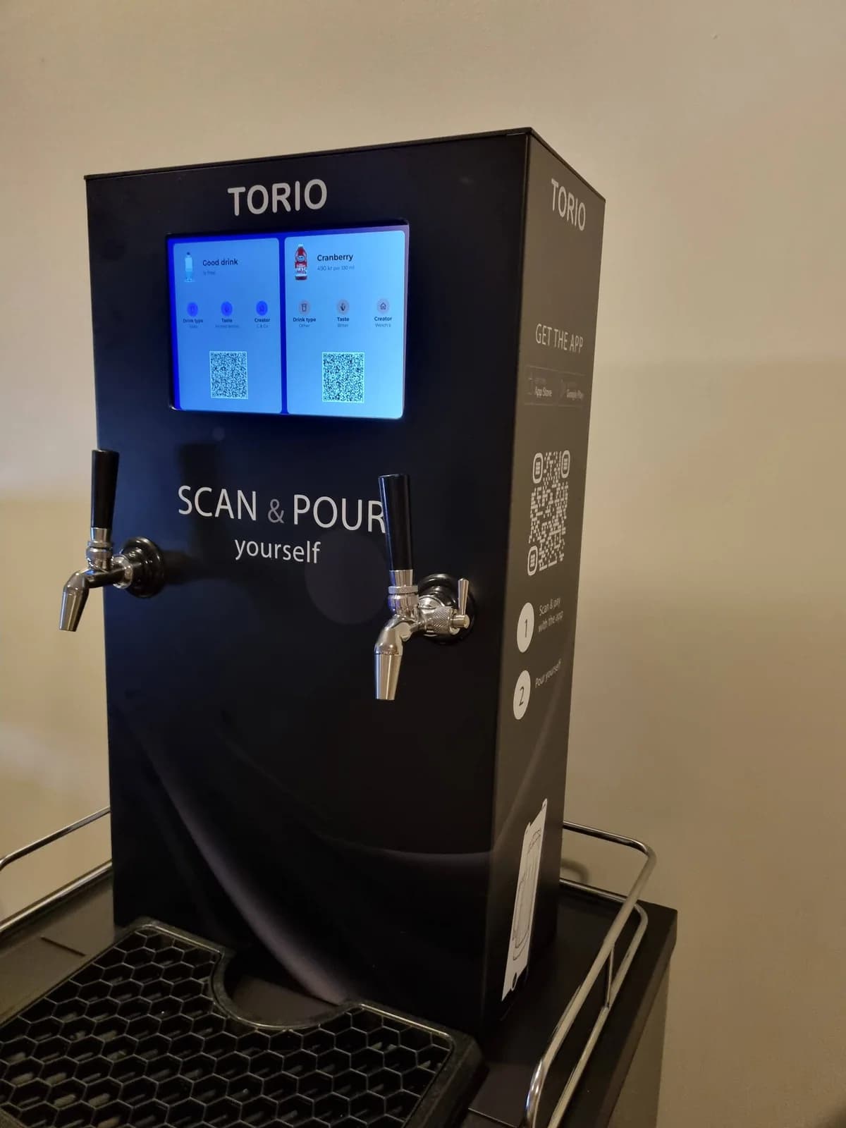 The enclosed Torio dispenser displaying drinks and QR codes above its two taps.