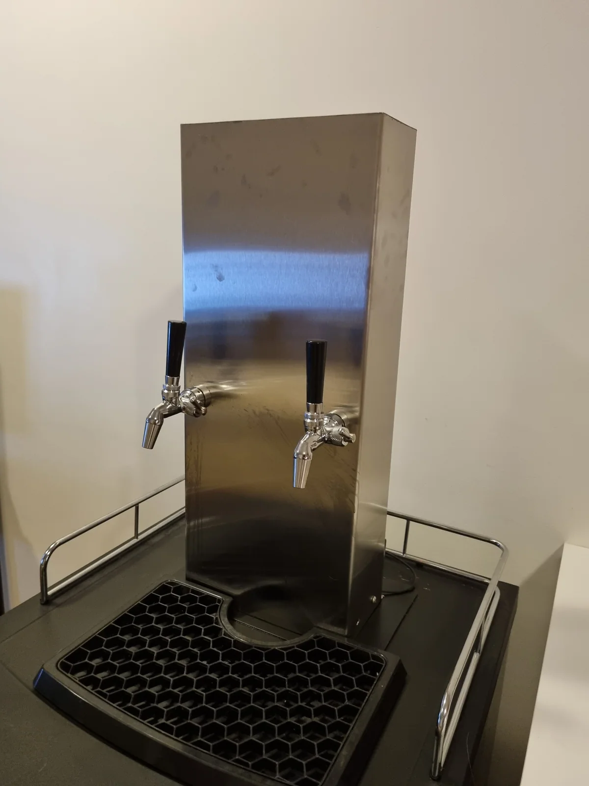 An early steel dispenser with two taps and a drip tray.