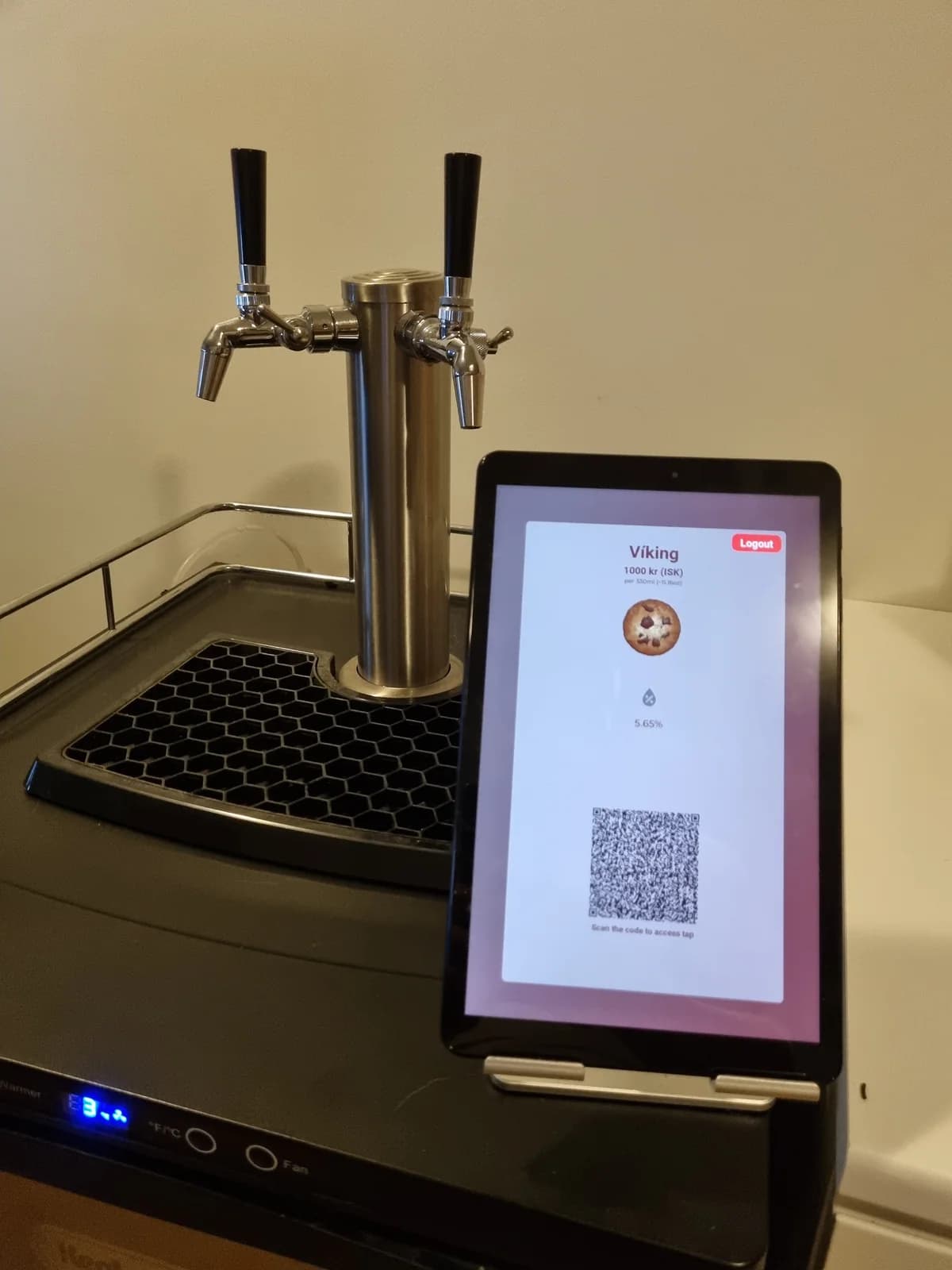 A tablet beside the steel prototype displaying a drink and QR code.