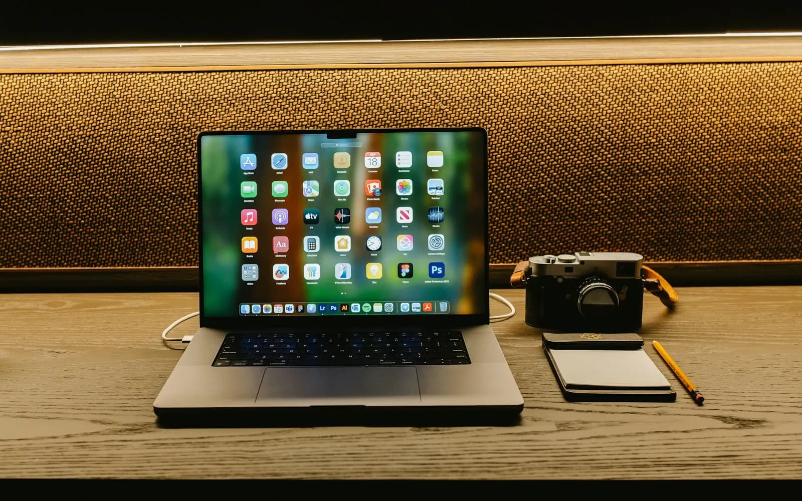 Laptop, camera and notepad arranged on a wooden desk