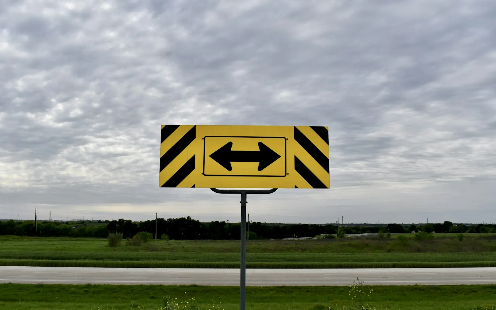 Yellow road sign with black arrows pointing left and right