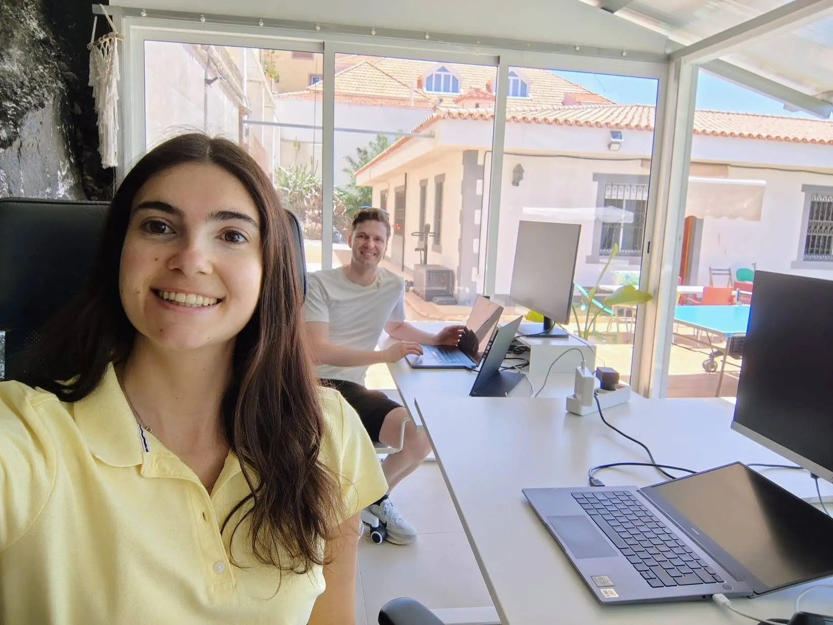 Two collaborators working on laptops inside the Blue Paradise coworking space.